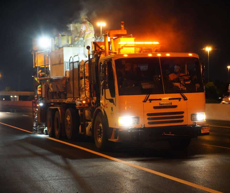 A thermoplastic pavement marking truck working at night.