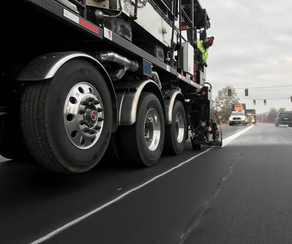 A Thermoplastic Pavement Marking truck working on a street with white paint.