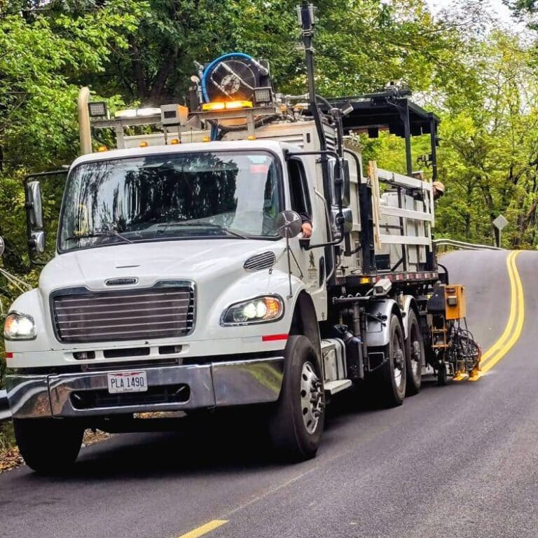 A large pavement marking truck painting yellow lines on a road.