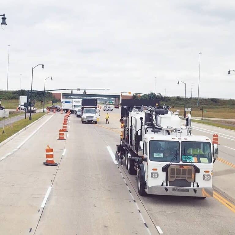 Several pavement marking trucks working on a highway.