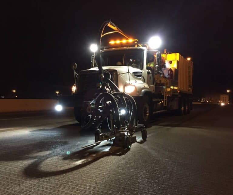 A pavement marking truck working on a highway at night.