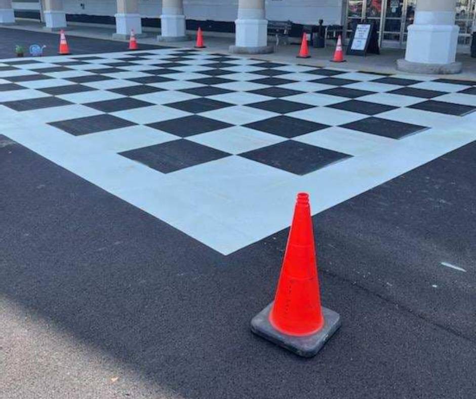 Safety cones on asphalt featuring a black and white checkered preformed marking tape
pattern.