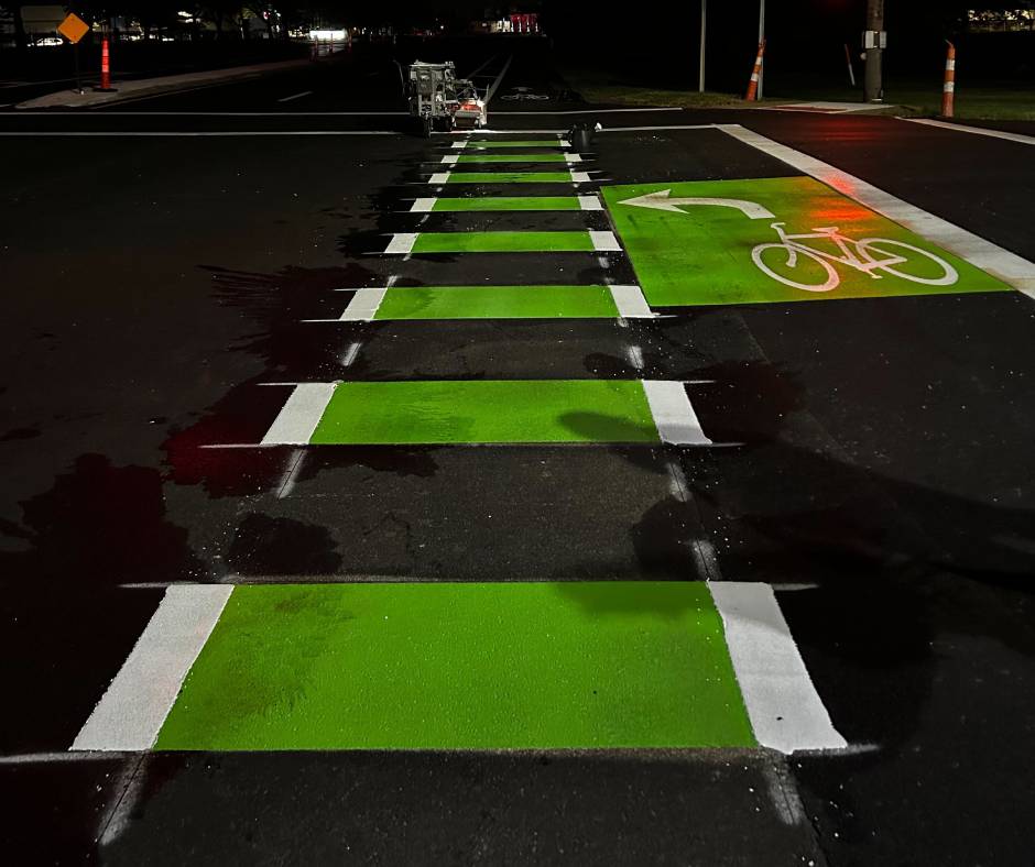 Green and black preformed marking tape on a road with a bicycle symbol designating a
bike path.