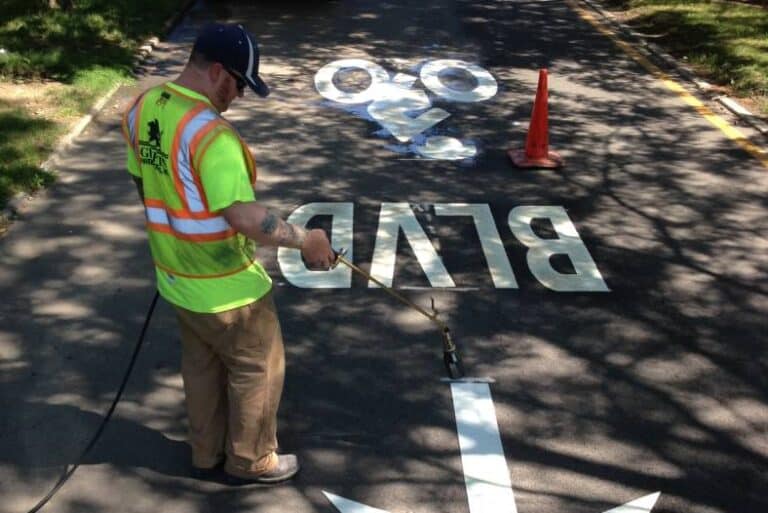 A worker applying preformed marking tape with a heating device.